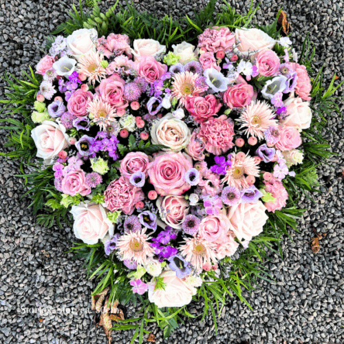 Begravningshjärta i mixade blommor i storleken stor. Hjärtat går i rosa och lila toner.