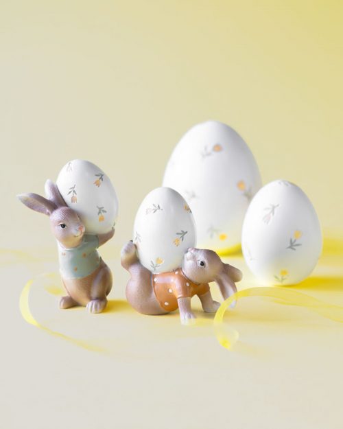Påskdekoration med två kaniner som håller målade ägg
